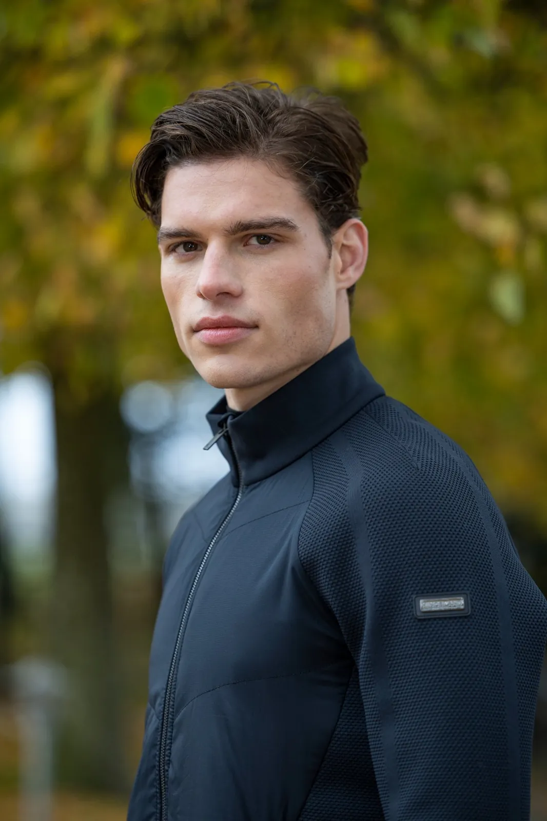Homme portant la veste hybride noire à col montant Kingsland Andy sous les arbres en automne.